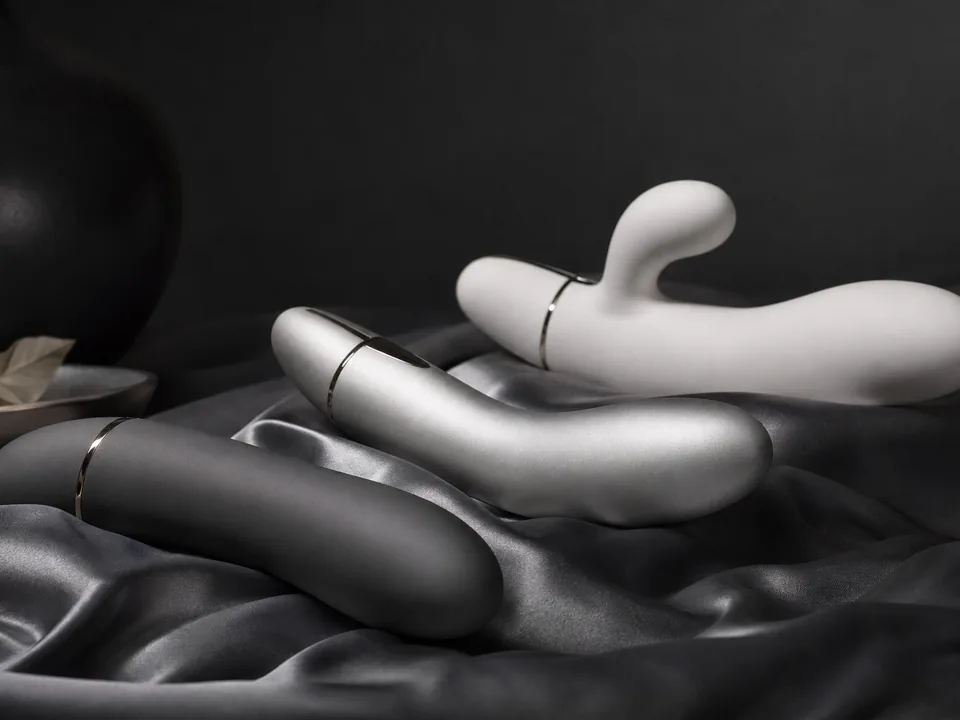 Three sleek personal massagers on folded grey silk